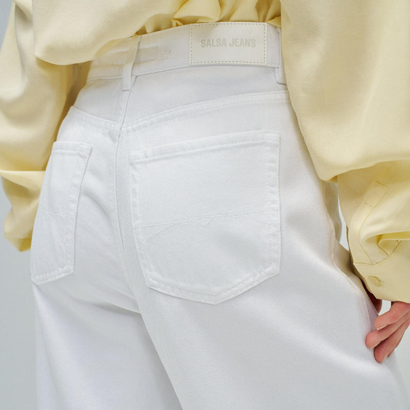 Calças jeans wide leg em branco puro que combinam estilo e conforto. O corte amplo na perna oferece liberdade de movimento e um visual moderno e descontraído. Equipadas com cinco bolsos funcionais, fecho de correr e botão na cintura para um ajuste seguro, além de presilhas para cinto. Peça versátil que funciona tanto em looks casuais como em composições mais sofisticadas.