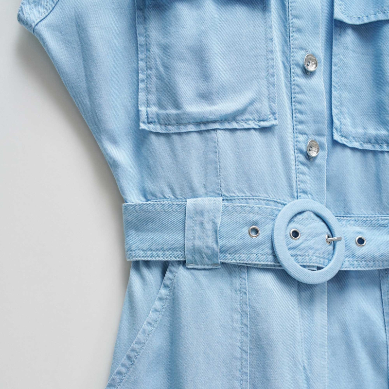 Macacão versátil em lightdenim azul claro que combina estilo casual com funcionalidade. Apresenta decote de colarinho clássico e mangas curtas, ideal para dias quentes. A silhueta cropped slim na perna oferece um visual moderno e ajustado. Fechamento prático com botões e fecho frontal, complementado por um cinto removível que permite ajustar o caimento conforme deseja. Seis bolsos estrategicamente posicionados — dois no peito, dois frontais funcionais e dois traseiros decorativos — garantem espaço para o es