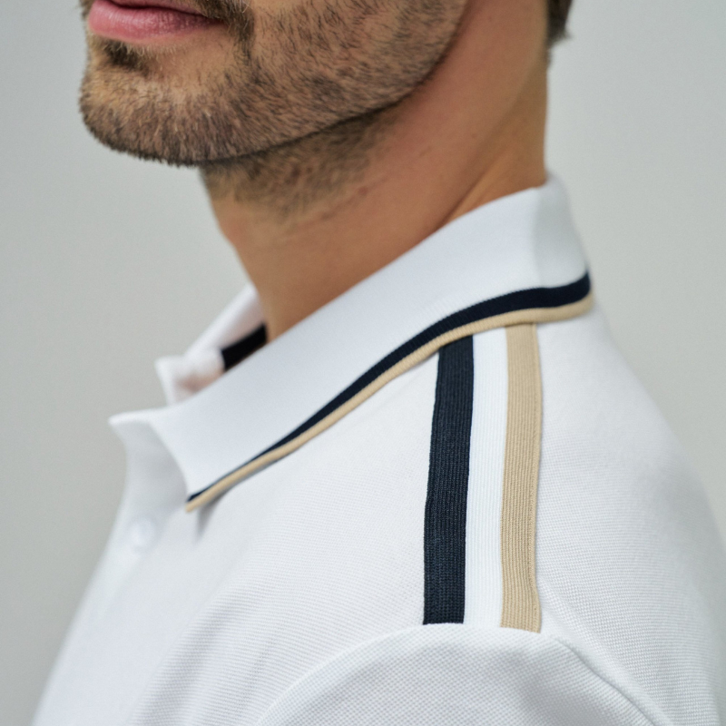 Polo clássico em branco com fit regular e mangas curtas. Apresenta decote de colarinho com botões e detalhe de riscas no colarinho que adiciona um toque de sofisticação. Perfeito para um visual casual e versátil, combina conforto com estilo contemporâneo. Ideal para o dia a dia ou ocasiões mais descontraídas.
