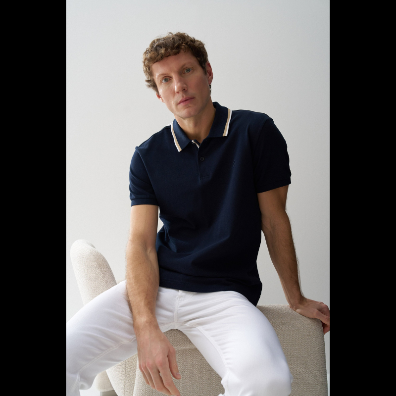 Polo clássico em Marinho com fit regular e mangas curtas. Apresenta decote de colarinho com botões e detalhe de riscas no colarinho que adiciona um toque de sofisticação. Perfeito para um visual casual e versátil, combina conforto com estilo contemporâneo. Ideal para o dia a dia ou ocasiões mais descontraídas.