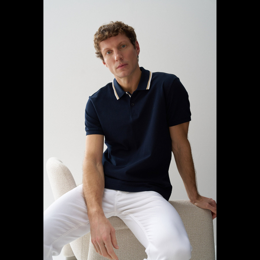 Polo clássico em Marinho com fit regular e mangas curtas. Apresenta decote de colarinho com botões e detalhe de riscas no colarinho que adiciona um toque de sofisticação. Perfeito para um visual casual e versátil, combina conforto com estilo contemporâneo. Ideal para o dia a dia ou ocasiões mais descontraídas.