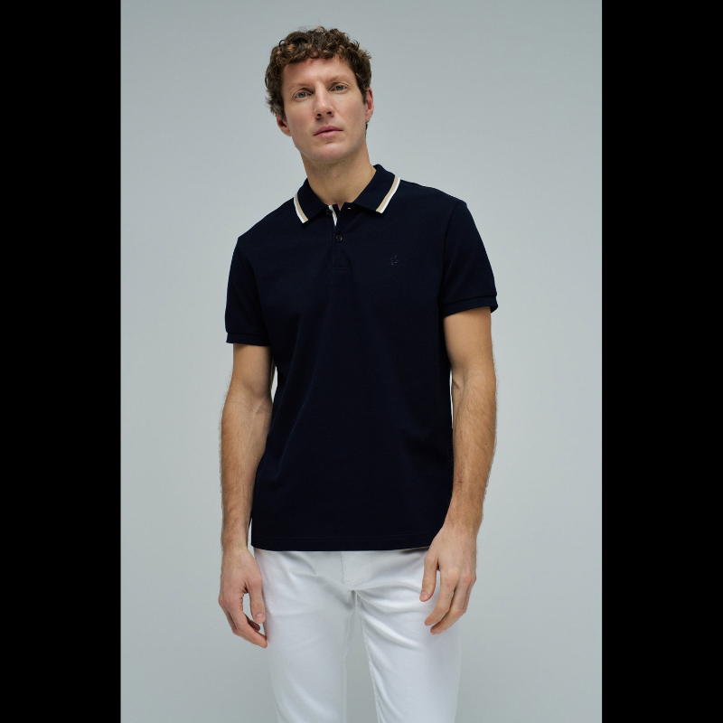 Polo clássico em Marinho com fit regular e mangas curtas. Apresenta decote de colarinho com botões e detalhe de riscas no colarinho que adiciona um toque de sofisticação. Perfeito para um visual casual e versátil, combina conforto com estilo contemporâneo. Ideal para o dia a dia ou ocasiões mais descontraídas.