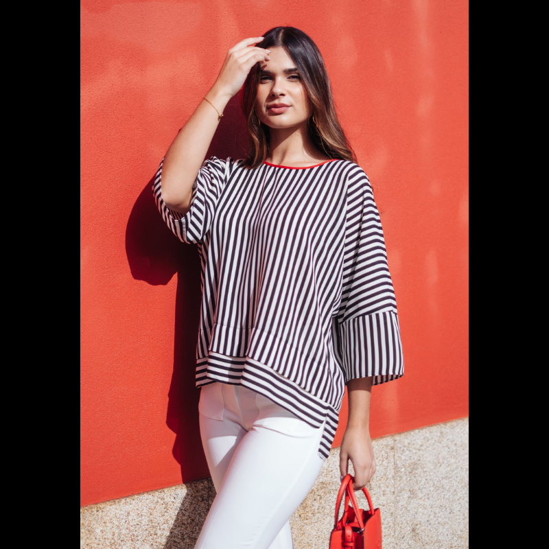 Túnica/Poncho oversize com riscas verticais em preto e branco que alongam a silhueta de forma sofisticada. O detalhe contrastante a vermelho no decote redondo adiciona carácter e modernidade. Corte amplo e comprimento assimétrico garantem conforto absoluto e um cair fluido. Versátil e fácil de conjugar, adapta-se a diferentes estilos, desde looks urbanos com calças de alfaiataria até registos descontraídos com jeans. Ideal para o dia a dia profissional criativo ou ocasiões onde o conforto não abdica da sofi