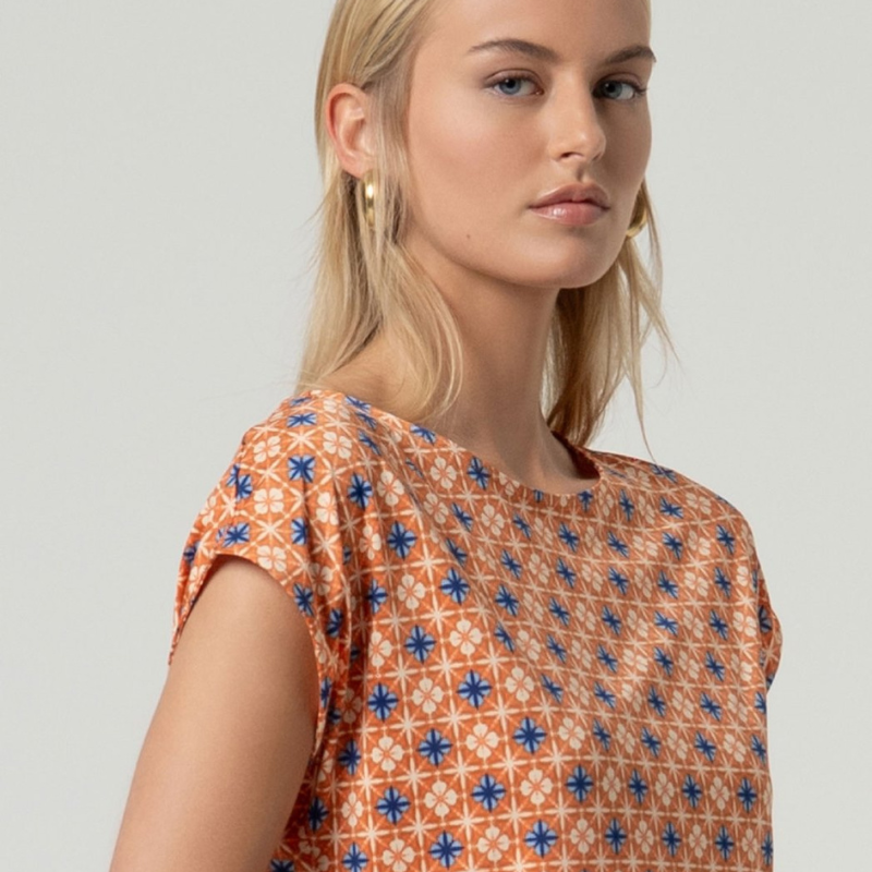 Camisola de decote em barco elegante com ombros ligeiramente caídos e corte reto que se adapta perfeitamente ao corpo. Camisola em laranja com estampado em azuis e areia. Tecido elástico e respirável, ideal para o dia a dia. Camisola versátil em poliéster reciclado com toque de Lycra para conforto e flexibilidade.