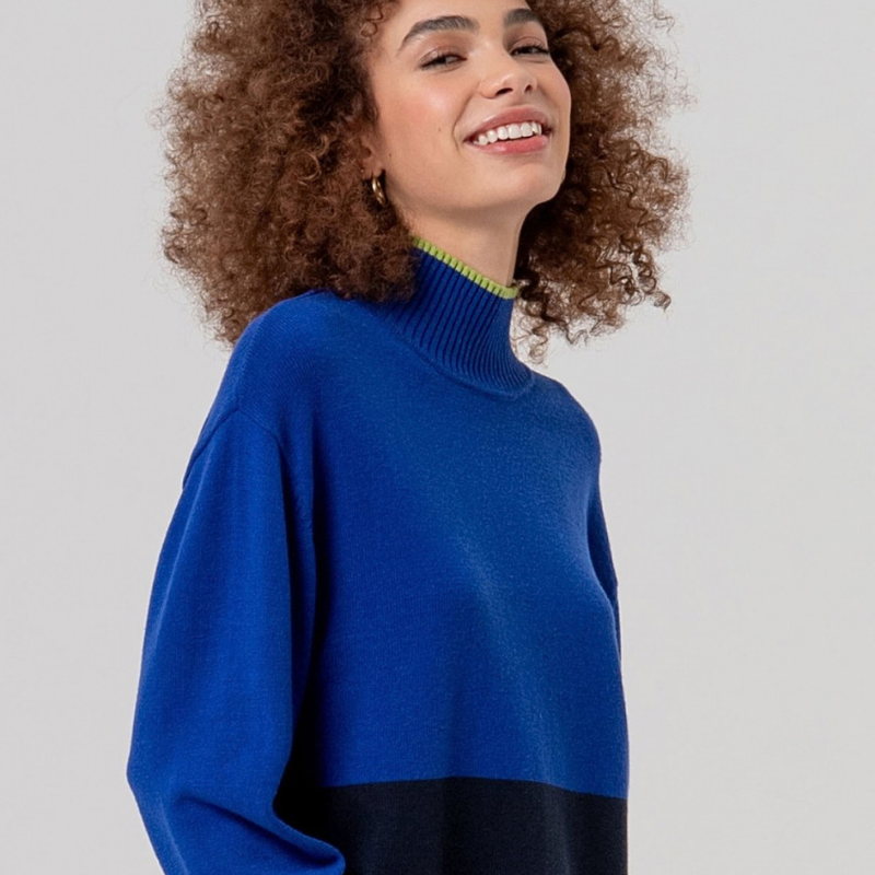 Camisola de manga comprida em malha com meia gola. Apresenta contrastes elegantes em azul cobalto e azul marinho, criando um visual sofisticado e versátil. Detalhes em risca verde claro na gola e punhos adicionam um toque de cor subtil e refinado. O cós é rematado com raxa de cada lado para um acabamento impecável