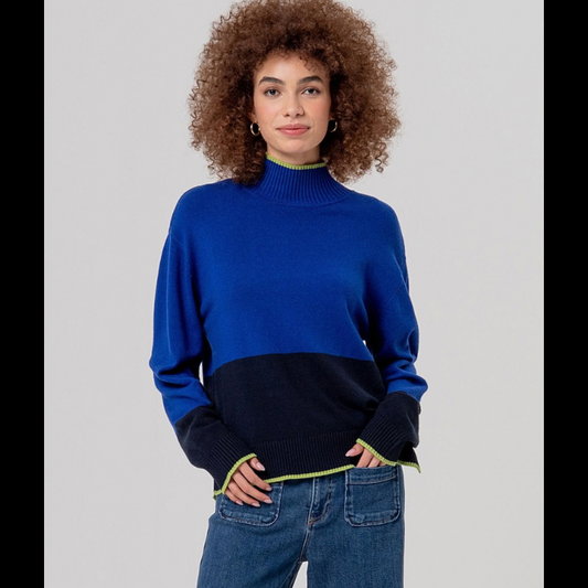 Camisola de manga comprida em malha com meia gola. Apresenta contrastes elegantes em azul cobalto e azul marinho, criando um visual sofisticado e versátil. Detalhes em risca verde claro na gola e punhos adicionam um toque de cor subtil e refinado. O cós é rematado com raxa de cada lado para um acabamento impecável