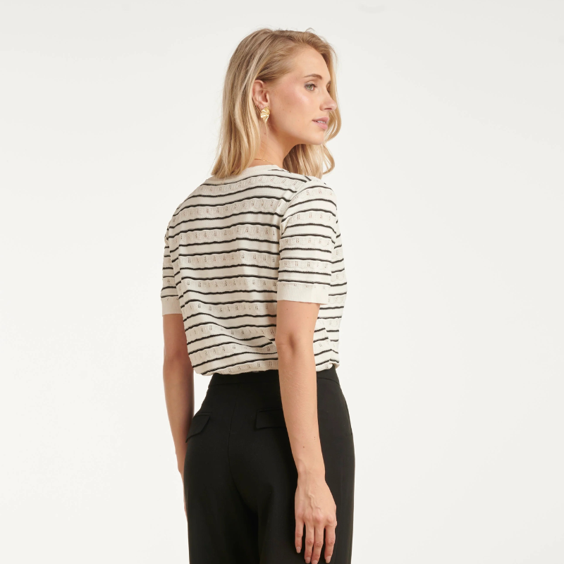 T-shirt de malha de manga curta em branco com riscas pretas. Pormenores de malha perfura na zona branca. Corte clássico com decote em V que oferece um visual elegante e versátil. Perfeita para combinar com qualquer look do dia a dia, esta peça é um essencial do guarda-roupa que funciona tanto em looks casuais como em composições mais sofisticadas.