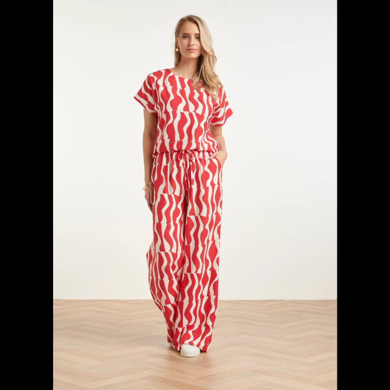 Blusa versátil em tons de vermelho e branco com estampa ondulada que traz movimento e personalidade ao visual. O decote redondo oferece conforto e elegância, enquanto as mangas curtas a tornam perfeita para dias quentes e transições de estação. Ideal para combinar com calças, saias ou shorts, esta peça é um essencial do guarda-roupa que funciona tanto em looks casuais como em ocasiões mais descontraídas.