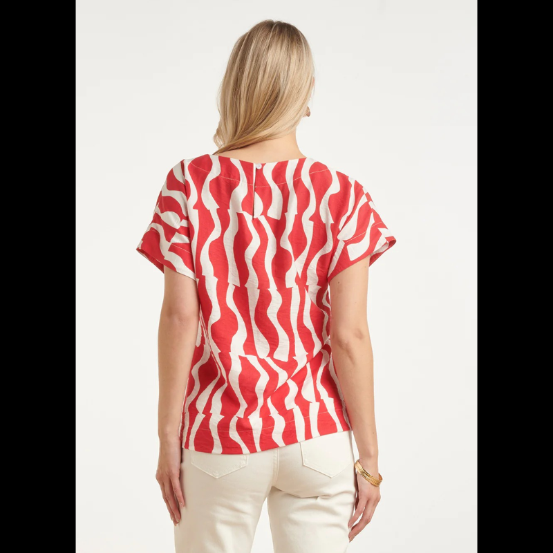 Blusa versátil em tons de vermelho e branco com estampa ondulada que traz movimento e personalidade ao visual. O decote redondo oferece conforto e elegância, enquanto as mangas curtas a tornam perfeita para dias quentes e transições de estação. Ideal para combinar com calças, saias ou shorts, esta peça é um essencial do guarda-roupa que funciona tanto em looks casuais como em ocasiões mais descontraídas.