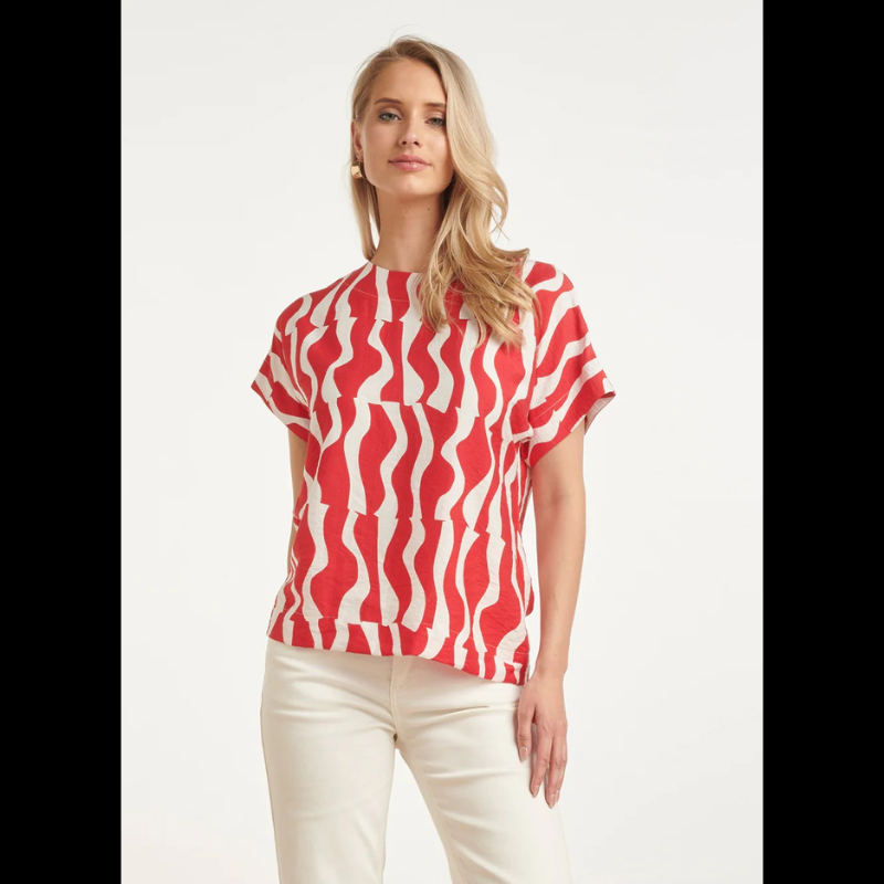 Blusa versátil em tons de vermelho e branco com estampa ondulada que traz movimento e personalidade ao visual. O decote redondo oferece conforto e elegância, enquanto as mangas curtas a tornam perfeita para dias quentes e transições de estação. Ideal para combinar com calças, saias ou shorts, esta peça é um essencial do guarda-roupa que funciona tanto em looks casuais como em ocasiões mais descontraídas.
