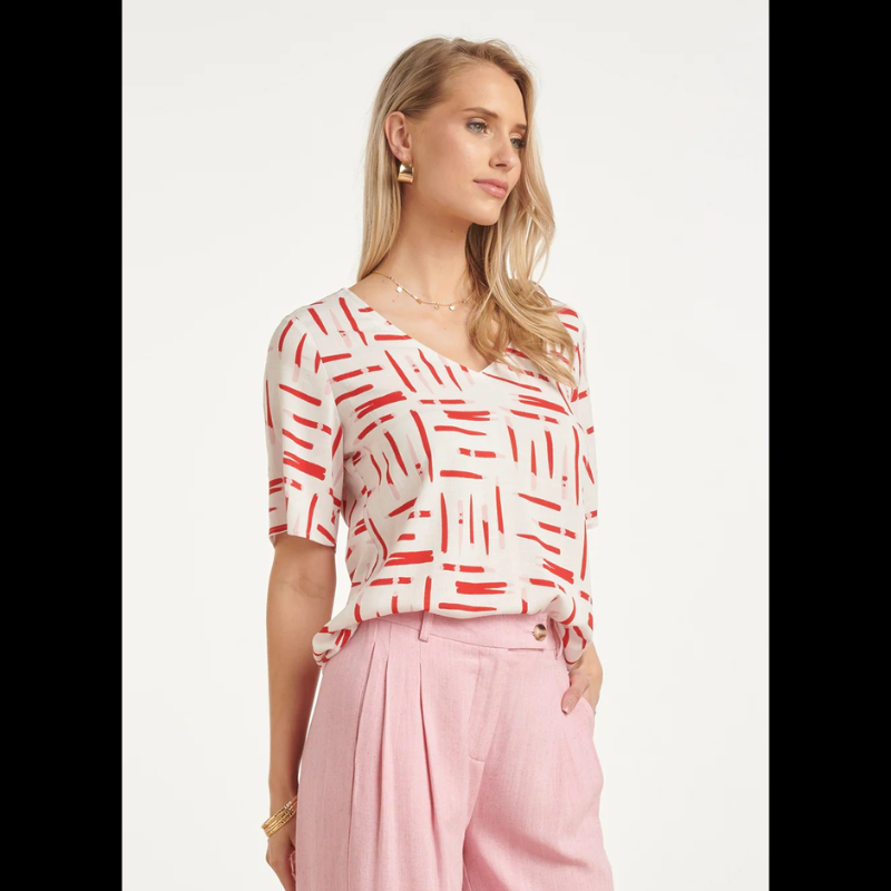 Blusa branca de manga curta com decote em V elegante e moderno. Apresenta um estampado gráfico exclusivo com riscas dinâmicas em vermelho e rosa que trazem movimento e personalidade ao design. Perfeita para criar looks casuais e descontraídos, combina facilmente com calças ou saias do seu guarda-roupa. Ideal para o dia a dia com um toque de estilo contemporâneo.