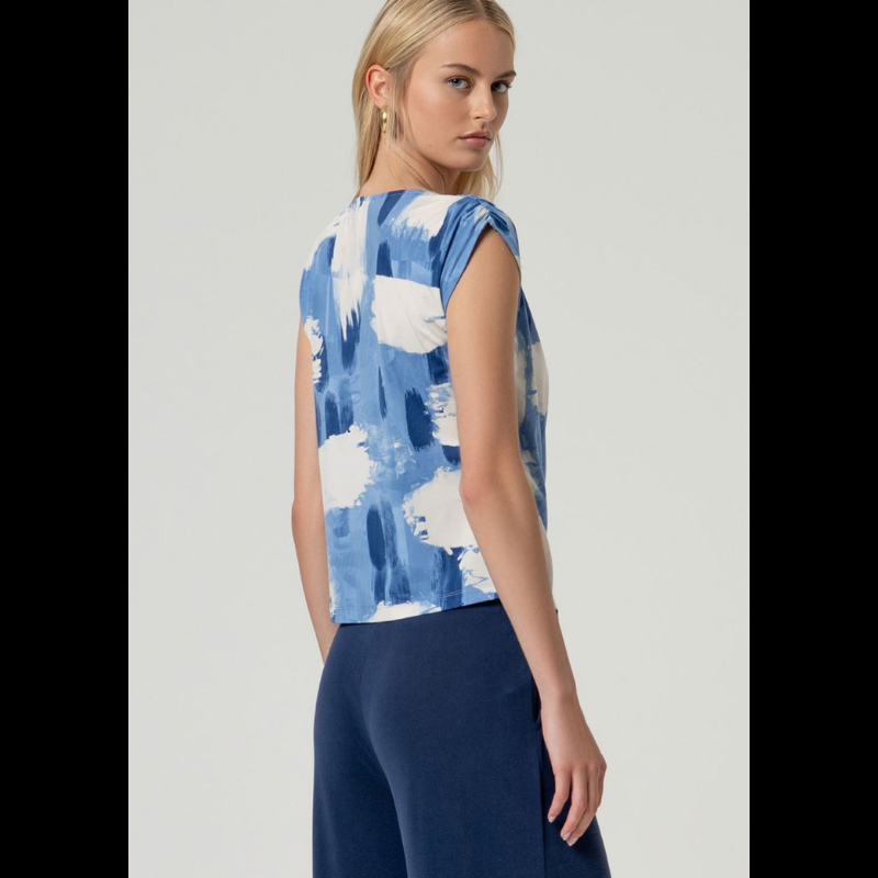 Descubra a elegância desta blusa sem mangas com decote drapeado sofisticado na frente e ombros delicadamente caídos. O corte reto oferece um ajuste perfeito ao corpo, realçando a sua silhueta de forma natural. Apresenta uma estampagem vibrante em tons de azul e branco que traz movimento e personalidade ao visual. A sua confeção combina sustentabilidade com conforto e flexibilidade para o seu dia a dia.