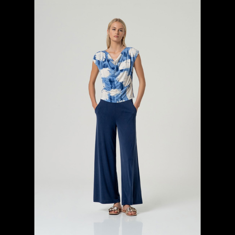 Descubra a elegância desta blusa sem mangas com decote drapeado sofisticado na frente e ombros delicadamente caídos. O corte reto oferece um ajuste perfeito ao corpo, realçando a sua silhueta de forma natural. Apresenta uma estampagem vibrante em tons de azul e branco que traz movimento e personalidade ao visual. A sua confeção combina sustentabilidade com conforto e flexibilidade para o seu dia a dia.