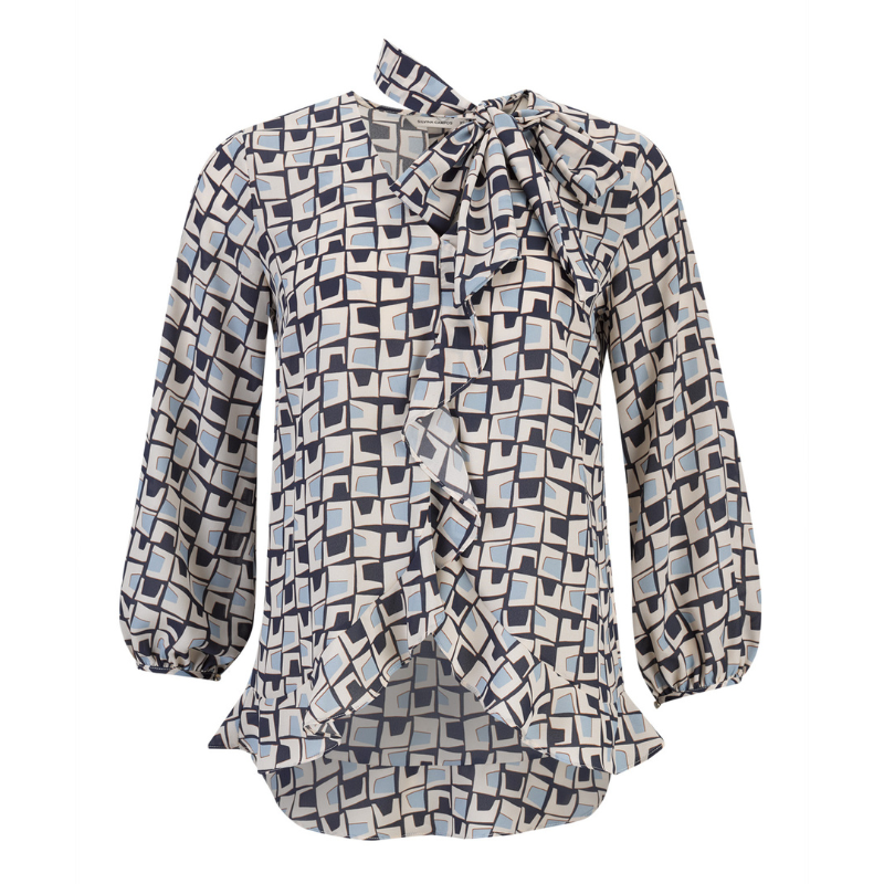Túnica com decote em V em estampado geométrico nos tons de azul marinho e creme que combina sofisticação e modernidade com um toque de criatividade, perfeita para coordenar com tons neutros para looks equilibrados ou com jeans para um visual casual-chic.
Túnica com assimetria do comprimento, mais comprida atrás do que à frente e com aplicação de folhos o que reforça o carácter contemporâneo da peça e acrescentam movimento e leveza ao design. O destaque vai para a laçada amovível no pescoço, no mesmo te