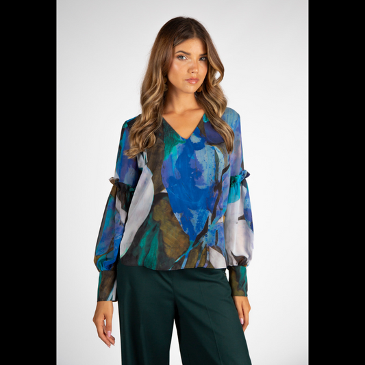 Túnica de decote em V com estampado abstrato em tons de turquesa, azul e verde. Túnica de mangas compridas em formato balão, levemente transparentes e forrada no corpo. Mangas a terminar com punho alto com dois botões metálicos em relevo.
Composição: 100%Poliester