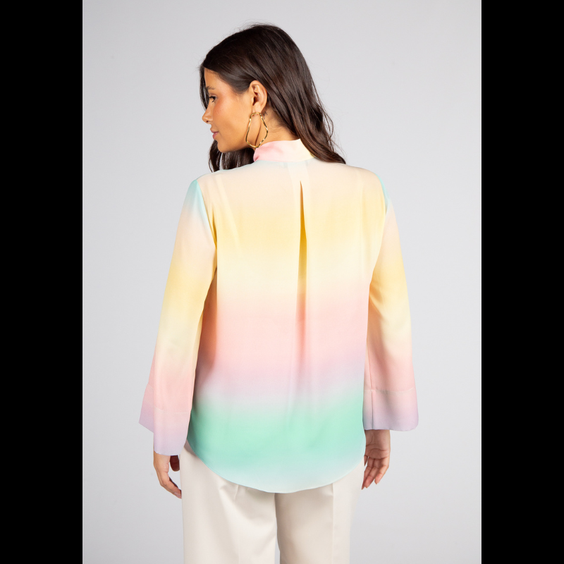 Túnica de decote em V com fita ajustável que oferece versatilidade de uso — mais solta para um visual descontraído ou ligeiramente ajustada para um efeito polido. As mangas compridas reforçam a adaptabilidade a diferentes estações e contextos. Túnica com estampado suave em tons pastel (rosa, amarelo, verde e azul) que cria um efeito etéreo e luminoso e transmite leveza e serenidade. Versátil para ambientes profissionais com calças de alfaiataria ou saias neutras, adapta-se também a coordenados descontraídos