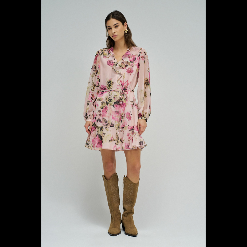 Vestido em tons rosa com padrão floral que combina elegância e movimento. O decote em V é realçado por folhos delicados, enquanto as mangas compridas apresentam punhos abotoados para um acabamento refinado. Destaca-se o cinto com pendentes nas extremidades, que adiciona dinamismo à silhueta. O folho na bainha confere volume e feminilidade. Vestido totalmente forrado para conforto e durabilidade. Uma peça versátil que transita com facilidade entre ocasiões casuais e mais sofisticadas.