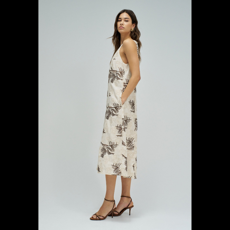 Vestido midi elegante em tons bege e castanho, perfeito para ocasiões especiais. Destaca-se pelos delicados bordados e missangas que adornam o tecido, criando um efeito sofisticado e refinado. Apresenta manga cava que oferece conforto e liberdade de movimento, com decote redondo clássico e feminino. Os bolsos funcionais adicionam praticidade ao design. A abertura nas costas com botão é um detalhe que confere sensualidade e movimento à peça. Ideal para eventos, jantares ou encontros especiais onde deseja des