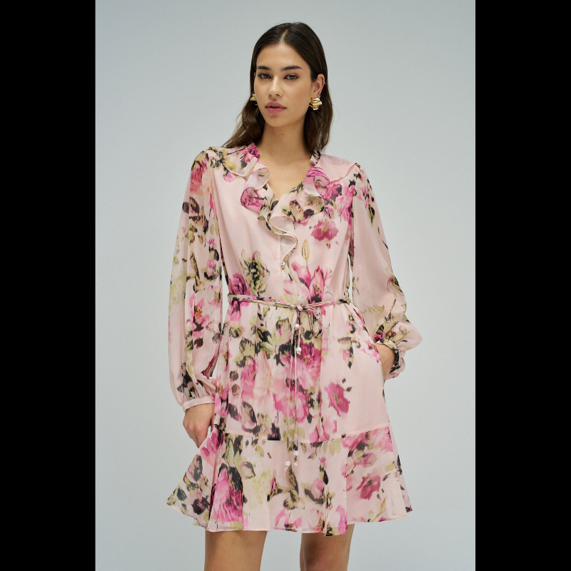 Vestido em tons rosa com padrão floral que combina elegância e movimento. O decote em V é realçado por folhos delicados, enquanto as mangas compridas apresentam punhos abotoados para um acabamento refinado. Destaca-se o cinto com pendentes nas extremidades, que adiciona dinamismo à silhueta. O folho na bainha confere volume e feminilidade. Vestido totalmente forrado para conforto e durabilidade. Uma peça versátil que transita com facilidade entre ocasiões casuais e mais sofisticadas.