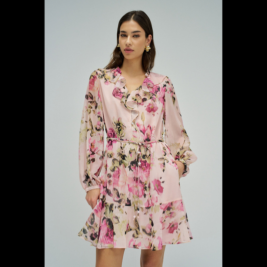 Vestido em tons rosa com padrão floral que combina elegância e movimento. O decote em V é realçado por folhos delicados, enquanto as mangas compridas apresentam punhos abotoados para um acabamento refinado. Destaca-se o cinto com pendentes nas extremidades, que adiciona dinamismo à silhueta. O folho na bainha confere volume e feminilidade. Vestido totalmente forrado para conforto e durabilidade. Uma peça versátil que transita com facilidade entre ocasiões casuais e mais sofisticadas.