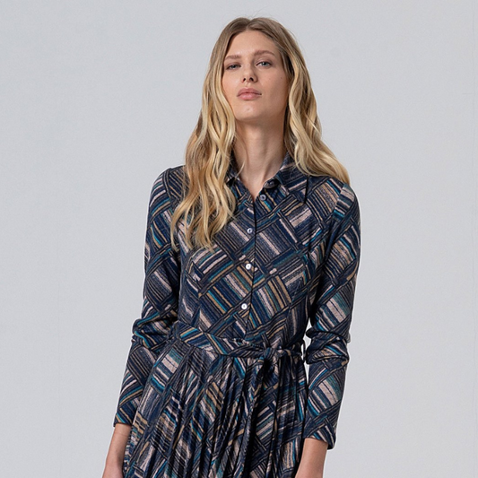 Vestido midi de mangas compridas com padrão geométrico em tons azuis e bege. Fecha na frente com botões até à cintura e termina com saia ligeiramente plissada. Vem acompanhado com cinto do mesmo tecido e padrão.
Composição: 50%Poliéster Reciclado + 45%Poliéster + 5%Elastano