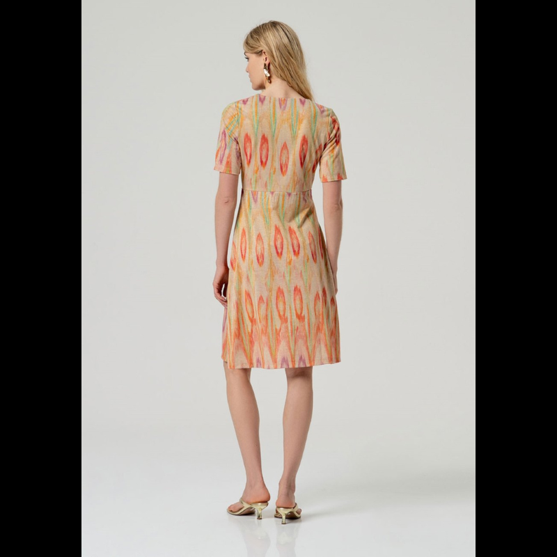 Vestido curto e de manga curta em malha fina que combina elegância e movimento. O decote em V e o fecho em traspasse no peito criam uma silhueta refinada e lisonjeira. O padrão geométrico em tons quentes—vermelho, laranja e verde—destaca-se sobre a base bege neutra, enquanto os fios de Lurex dourado adicionam um toque de sofisticação e luminosidade. Uma escolha contemporânea para quem valoriza detalhes bem executados e design atemporal.