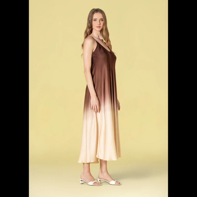 Vestido comprido em acetinado bicolor que combina castanho e bege numa harmonia sofisticada. Alças finas ajustáveis permitem um ajuste personalizado ao seu corpo. Decote em V elegante que enquadra perfeitamente o busto. Peça versátil ideal para ocasiões especiais ou eventos noturnos, oferecendo conforto e estilo em igual medida.