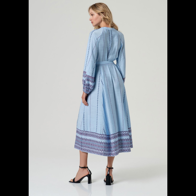 Vestido camiseiro midi em azul com cintura marcada e decote em V elegante. Mangas compridas com elástico nos punhos e detalhes de bordado geométrico em marinho e bordô. Faixa bordada na barra e nos punhos adiciona sofisticação. Fecha na frente com botões em azul claro e vem acompanhado por um cinto do mesmo tecido e padrão. Peça versátil perfeita para o dia a dia com um toque de refinamento.