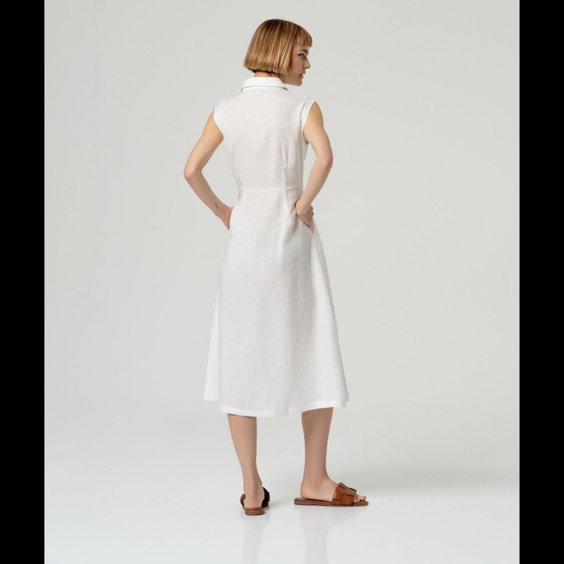Vestido camiseiro sem mangas em linho e viscose, combinando conforto e elegância. O corte ajustado na cintura realça a silhueta, enquanto a saia em corte envolvente oferece movimento e fluidez. Perfeito para dias quentes, transita facilmente do casual ao sofisticado. Tecido respirável que acompanha o corpo com naturalidade.