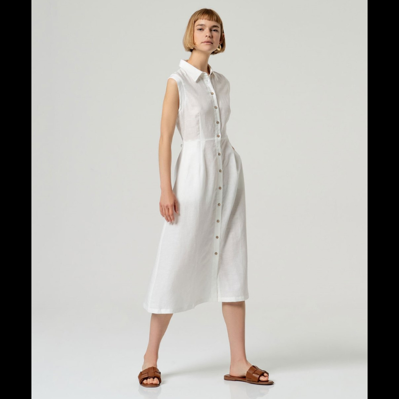 Vestido camiseiro sem mangas em linho e viscose, combinando conforto e elegância. O corte ajustado na cintura realça a silhueta, enquanto a saia em corte envolvente oferece movimento e fluidez. Perfeito para dias quentes, transita facilmente do casual ao sofisticado. Tecido respirável que acompanha o corpo com naturalidade.
