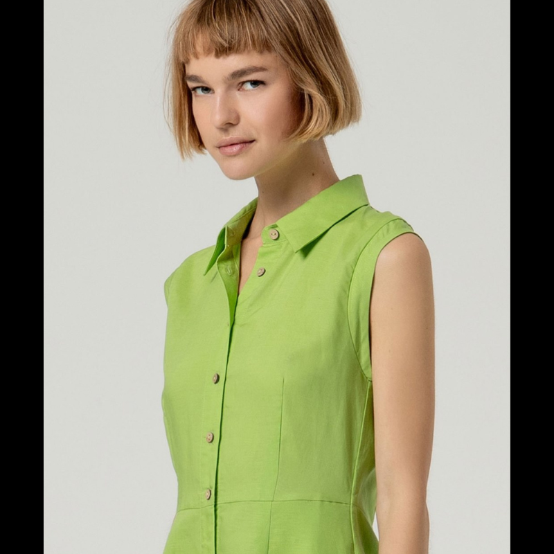 Vestido camiseiro verde sem mangas em linho e viscose, combinando conforto e elegância. O corte ajustado na cintura realça a silhueta, enquanto a saia em corte envolvente oferece movimento e fluidez. Perfeito para dias quentes, transita facilmente do casual ao sofisticado. Tecido respirável que acompanha o corpo com naturalidade.
