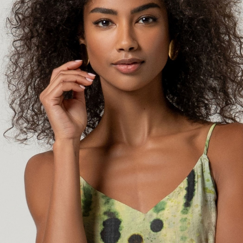Vestido comprido em viscose e poliamida que combina elegância e conforto. Decote em V com alças finas ajustáveis e fecho invisível nas costas para um acabamento impecável. O corte estruturado no peito contrasta com a saia fluida forrada, enquanto a abertura lateral frontal adiciona movimento e modernidade. O padrão abstrato em tons verdes traz sofisticação a este design versátil, perfeito para ocasiões especiais ou uso do dia a dia elevado.