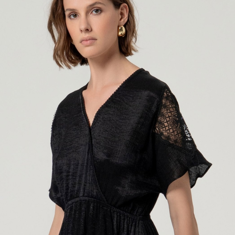 Descubra elegância e conforto com este vestido longo SURKANA em preto brilhante. O decote em V cruzado com mola invisível cria uma silhueta sofisticada, enquanto as mangas curtas soltas com detalhes de renda adicionam um toque feminino. O ajuste elástico entre a cintura e o peito proporciona um caimento solto e fluido, complementado pelas aberturas laterais que garantem liberdade de movimento. Perfeito para ocasiões especiais ou para um look noturno elegante.