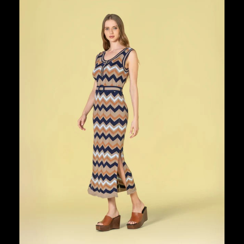 Vestido versátil em malha com decote redondo e cavas generosas, apresentando um padrão geométrico em zigzag que combina taupe, azul-marinho, azul-claro e caramelo. O corte midi é complementado por duas aberturas laterais que conferem movimento e conforto. Inclui cinto coordenado nos mesmos tons, permitindo ajustar o caimento conforme desejado. Uma escolha sofisticada para quem valoriza design contemporâneo e funcionalidade.