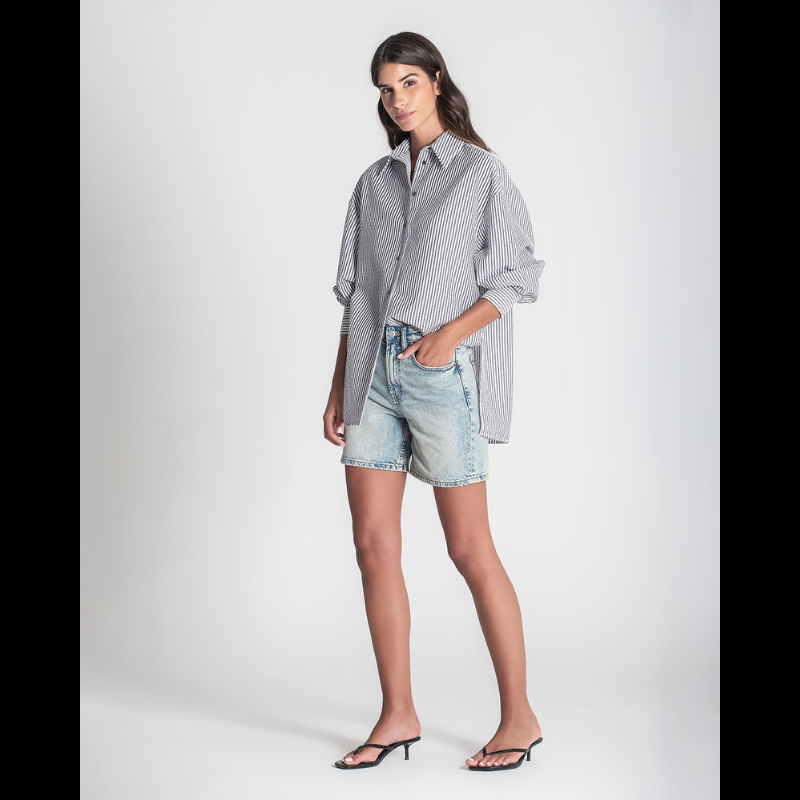 Camisa "oversize" de manga comprida às riscas brancas e cinza. Camisa a fechar na frente e punhos com botões cinzentos. Abertura nas laterias
Composição: 65%Poliéster + 35%Algodão